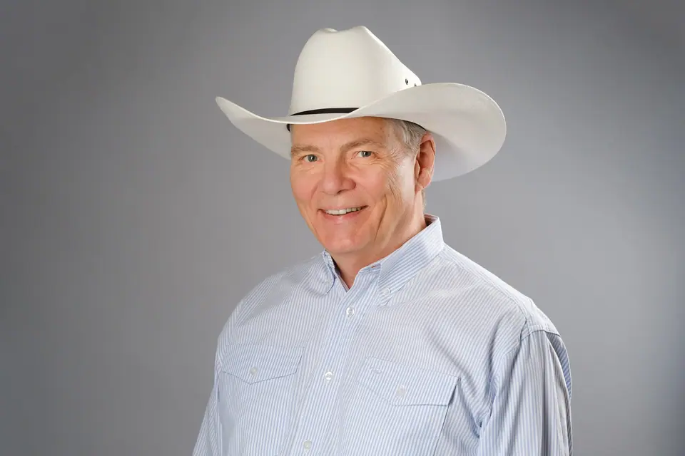 Character actor headshot of a smiling man in a white cowboy hat
