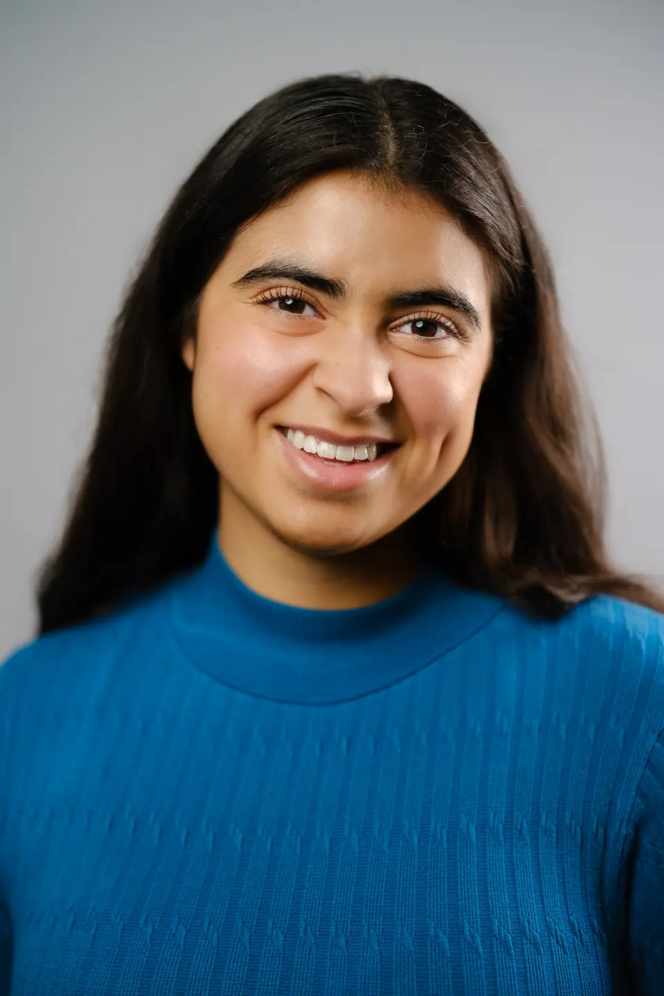 Actor headshot of a smiling woman in a blue knit sweater