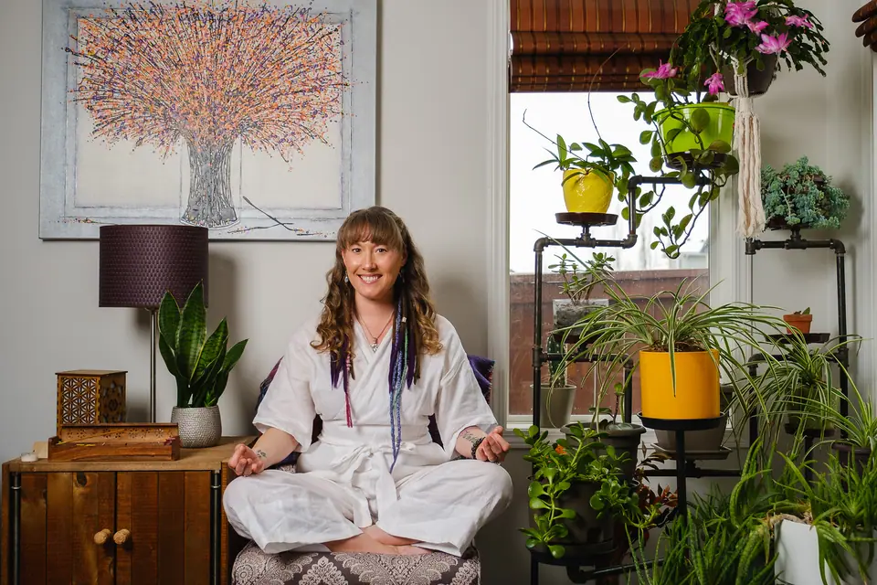 Personal branding portrait of a woman seated in a bright room full of plants