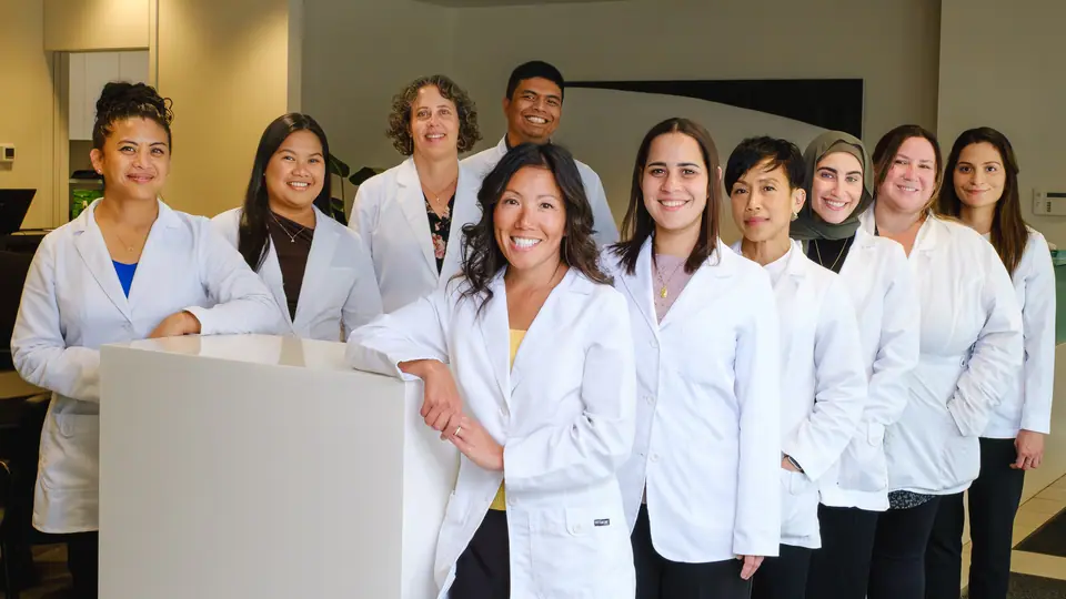 On location team photo of eye clinic staff in white coats at their front desk