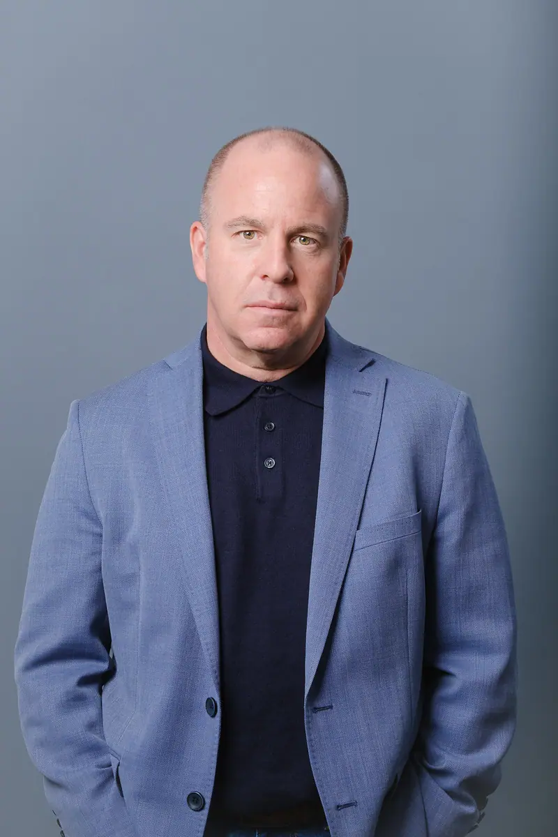 Portrait of a man in a light blue blazer on a grey backdrop