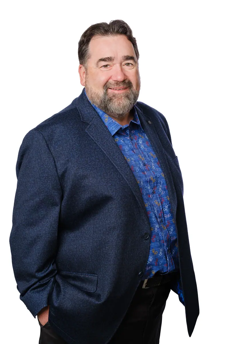 Corporate portrait of a man in a navy blazer and patterned shirt