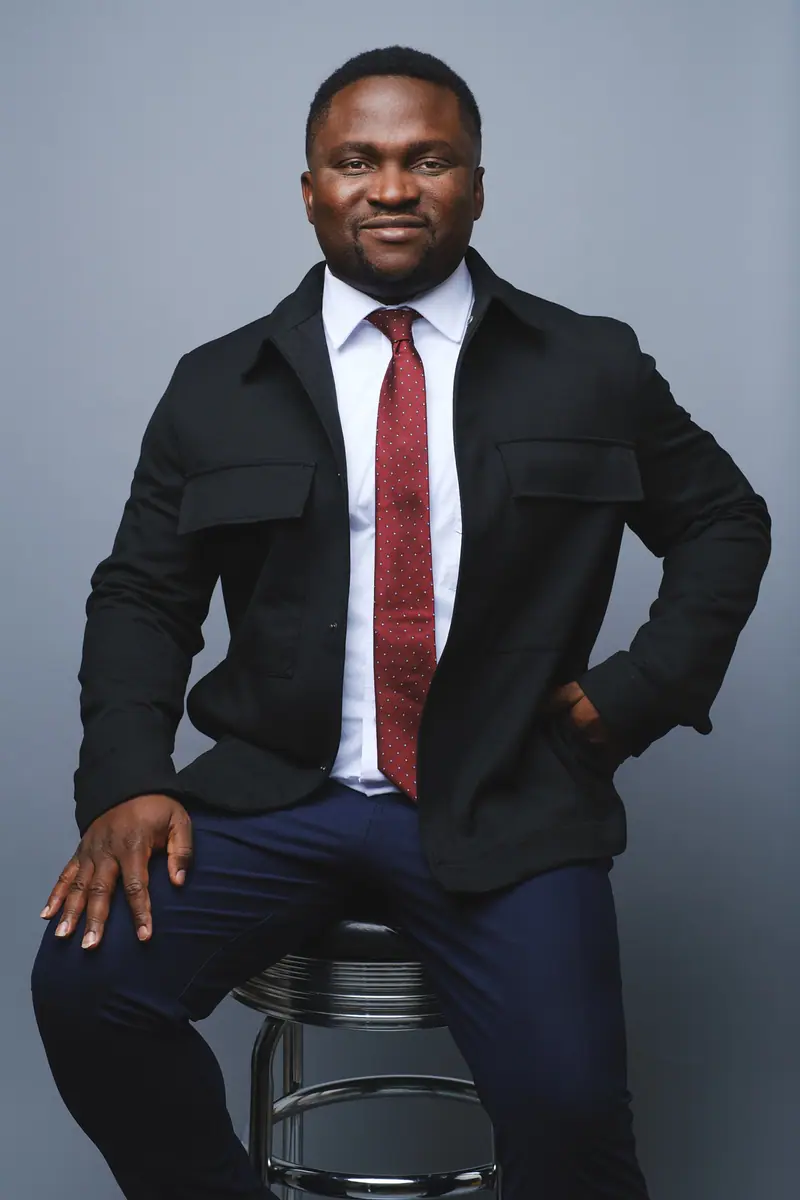 Seated corporate portrait of a man in a dark suit and red tie