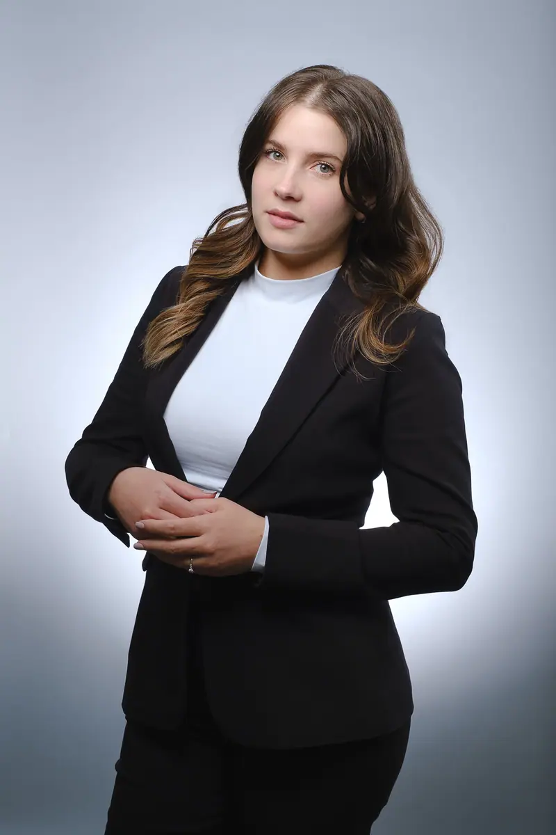 Three quarter portrait of a woman in a black blazer on a light backdrop