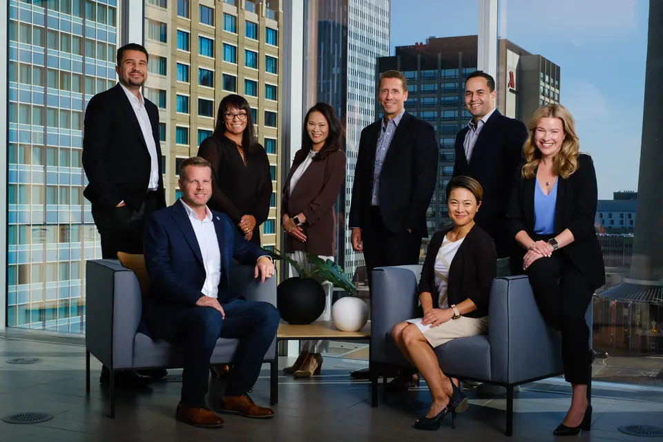 Corporate team photo of ten colleagues in an office with downtown Calgary views