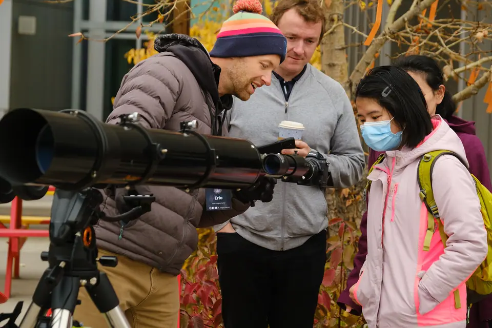 Guests looking through a telescope at a public eclipse viewing event
