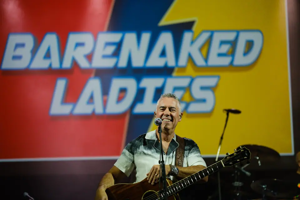 Musician performing at a charity gala in front of a bright band banner
