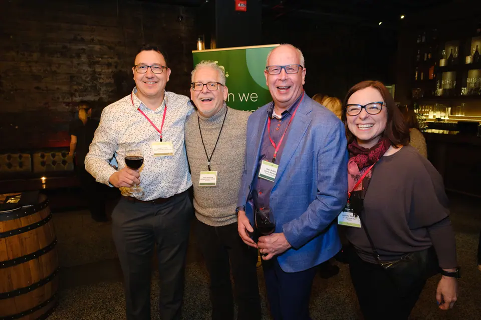 Four smiling guests posing together at a networking reception
