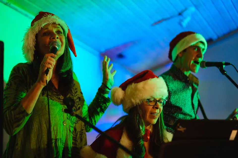 Performers in Santa hats singing at a company holiday party