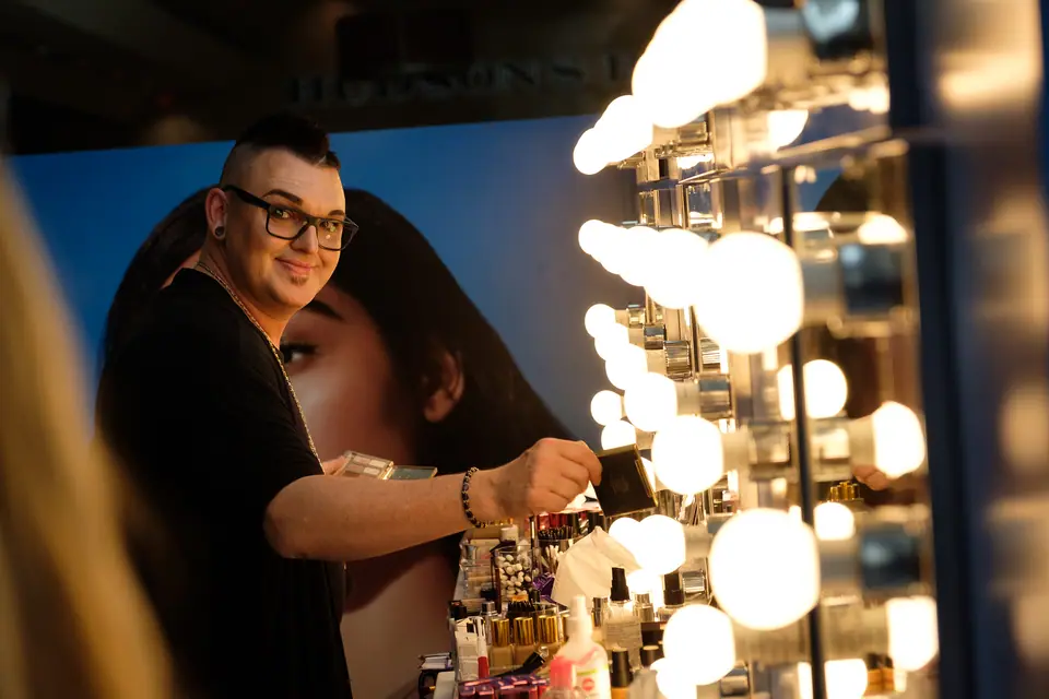 Makeup artist at a lit mirror during a brand activation