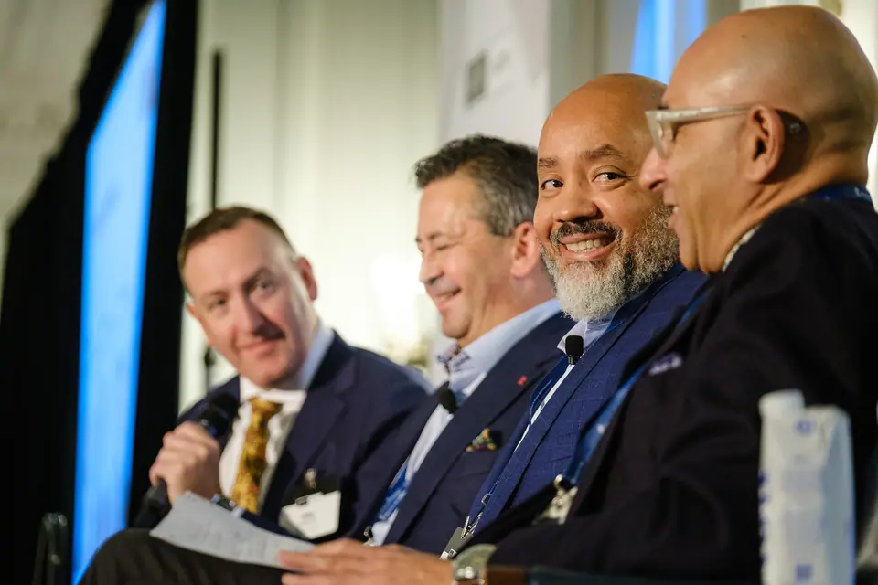 Conference panel of business leaders laughing during a discussion