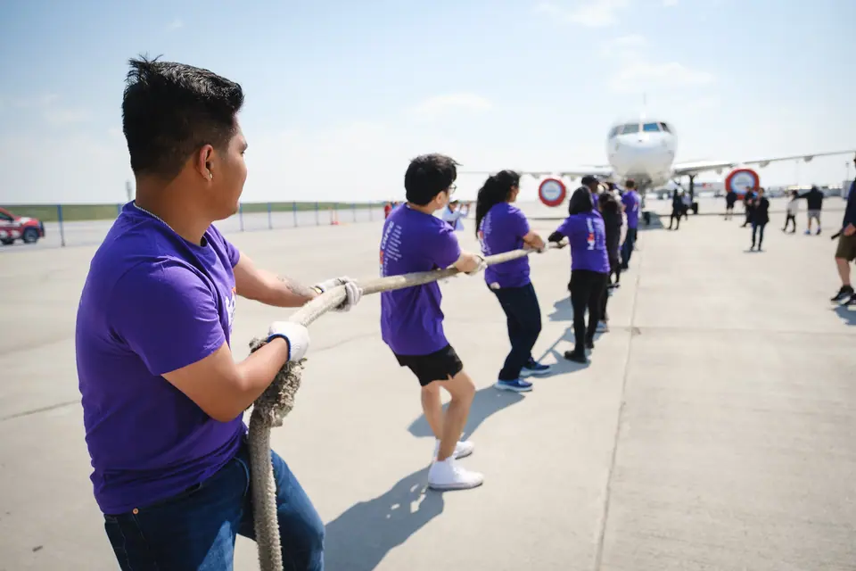 Charity plane pull event with teams in purple shirts pulling a jet on the tarmac