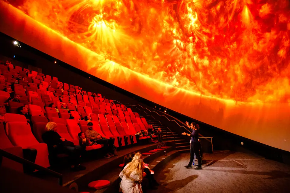 Presenter in a planetarium dome with a giant projection of the sun