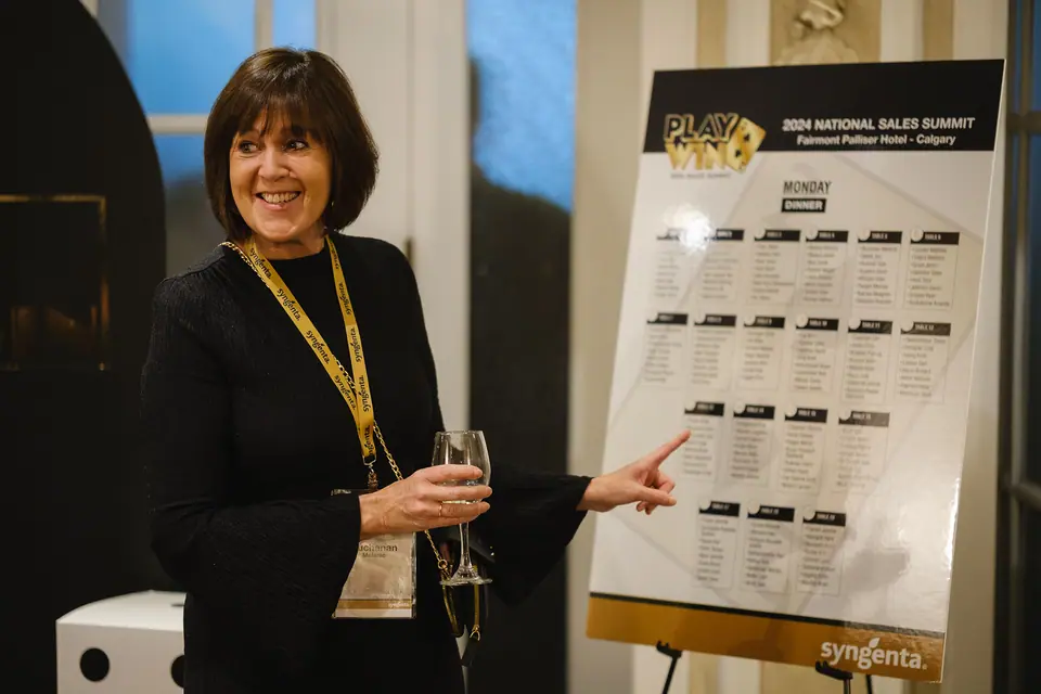 Event host smiling beside a seating chart at a sales summit