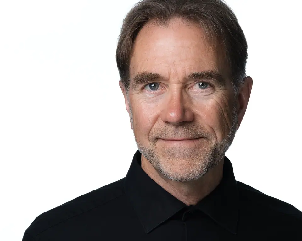 Actor style headshot of a man with grey hair in a black shirt