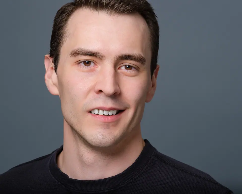 Casual headshot of a man with dark hair in a black t shirt
