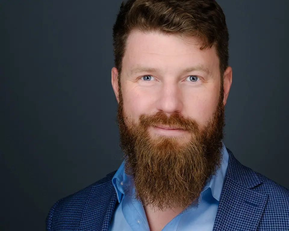 Headshot of a man with a full beard in a blue blazer