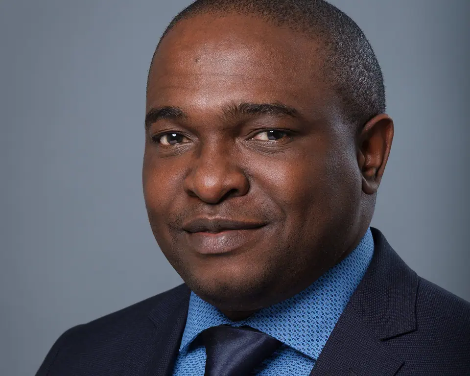 Executive headshot of a man in a navy suit and light blue shirt
