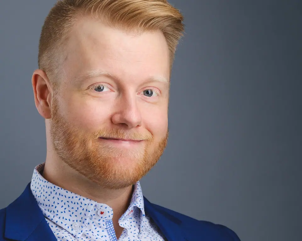 Friendly headshot of a man with red hair in a blue blazer