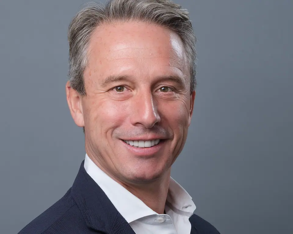 Executive headshot of a man with silver hair and an open collar