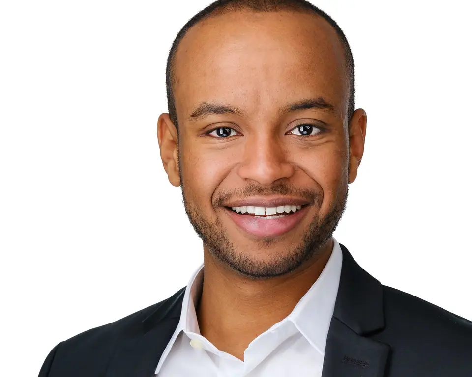 Clean white background headshot of a smiling man in a dark suit