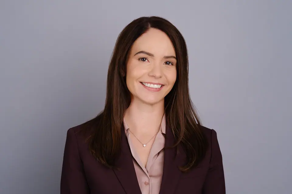 Professional headshot of a smiling woman in a burgundy blazer