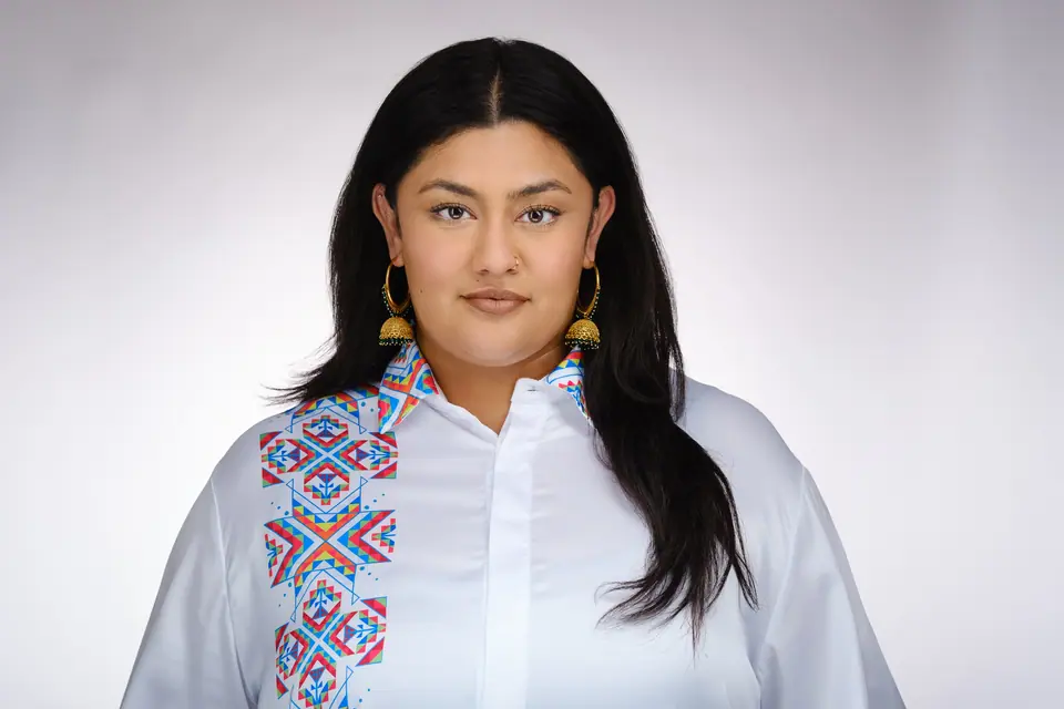 Headshot of a woman with long dark hair in an embroidered white shirt