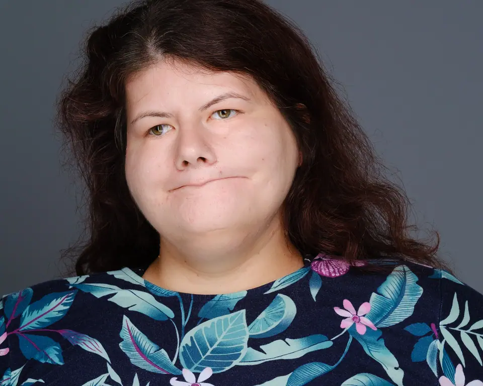Headshot of a woman with dark curly hair in a floral top