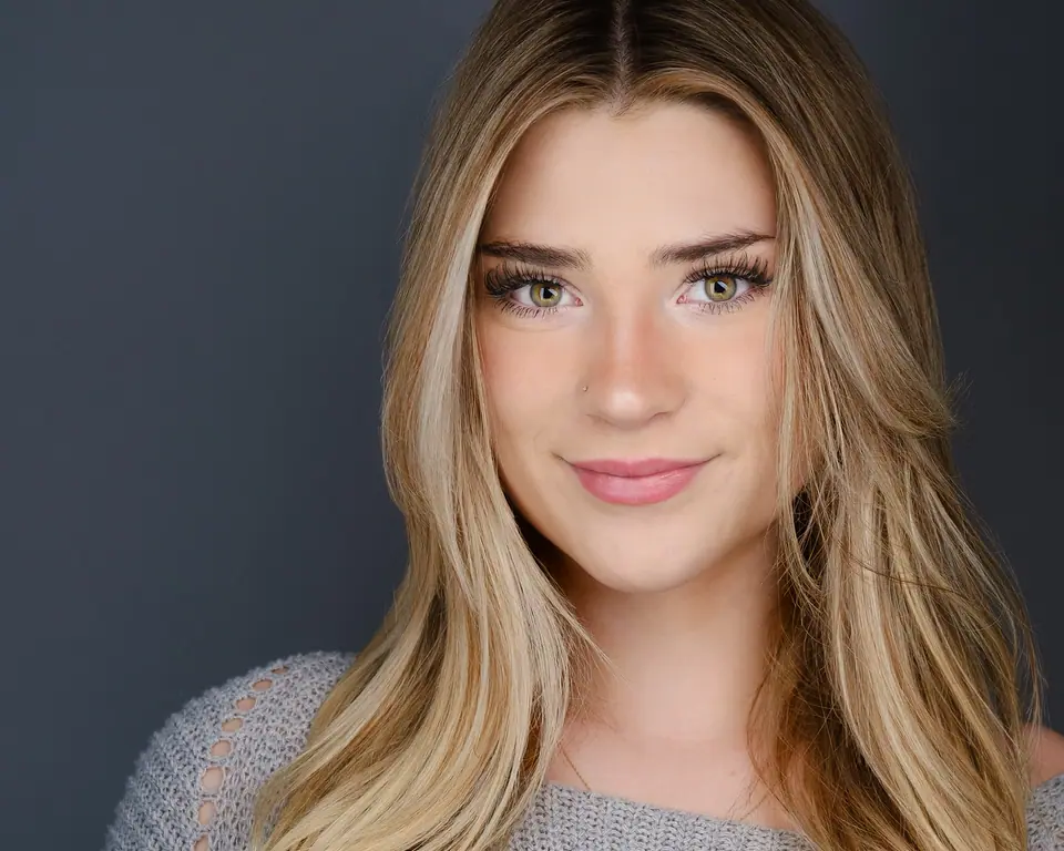 Studio headshot of a young woman with long blonde hair on a charcoal backdrop