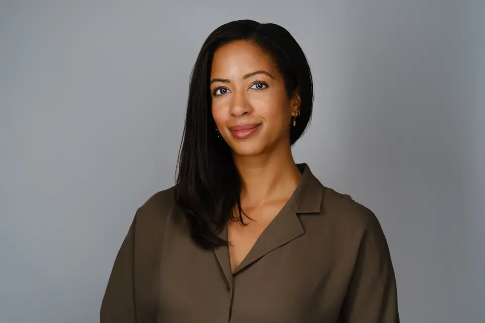 Professional headshot of a woman with long dark hair in an olive blouse