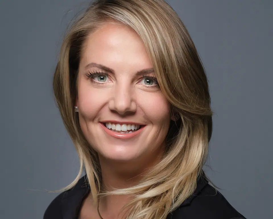 Warm professional headshot of a smiling woman with layered blonde hair