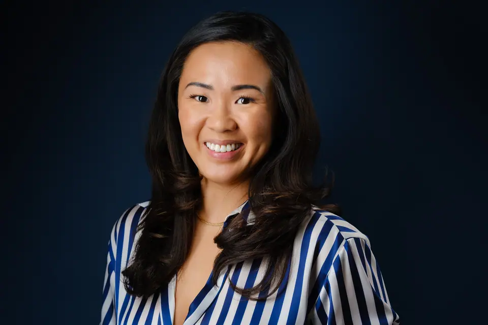 Headshot of a smiling woman with long dark hair in a striped blouse