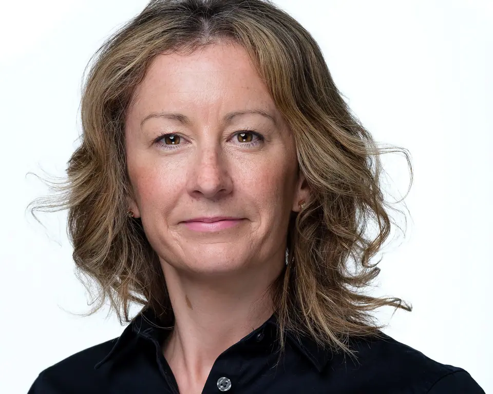 Light background headshot of a woman with wavy hair in a black blouse