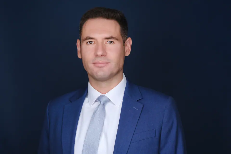 Healthcare professional headshot of a man in a blue suit on a navy backdrop