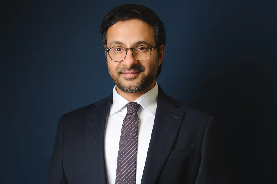 Lawyer headshot of a man with glasses in a dark suit and tie