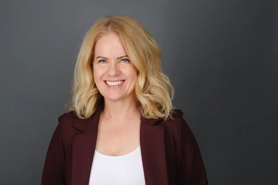 Lawyer headshot of a smiling woman with blonde hair in a burgundy blazer