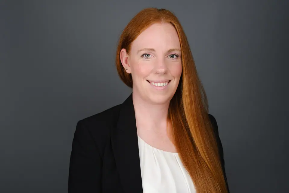 Lawyer headshot of a smiling woman with long red hair in a black blazer
