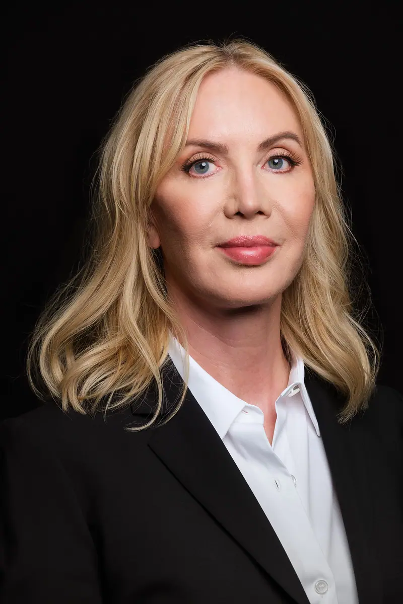 Portrait of a woman with blonde hair in a black blazer on black