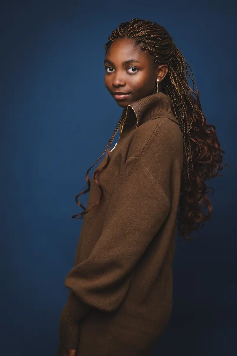 Fashion style portrait of a woman with long braids in a brown coat