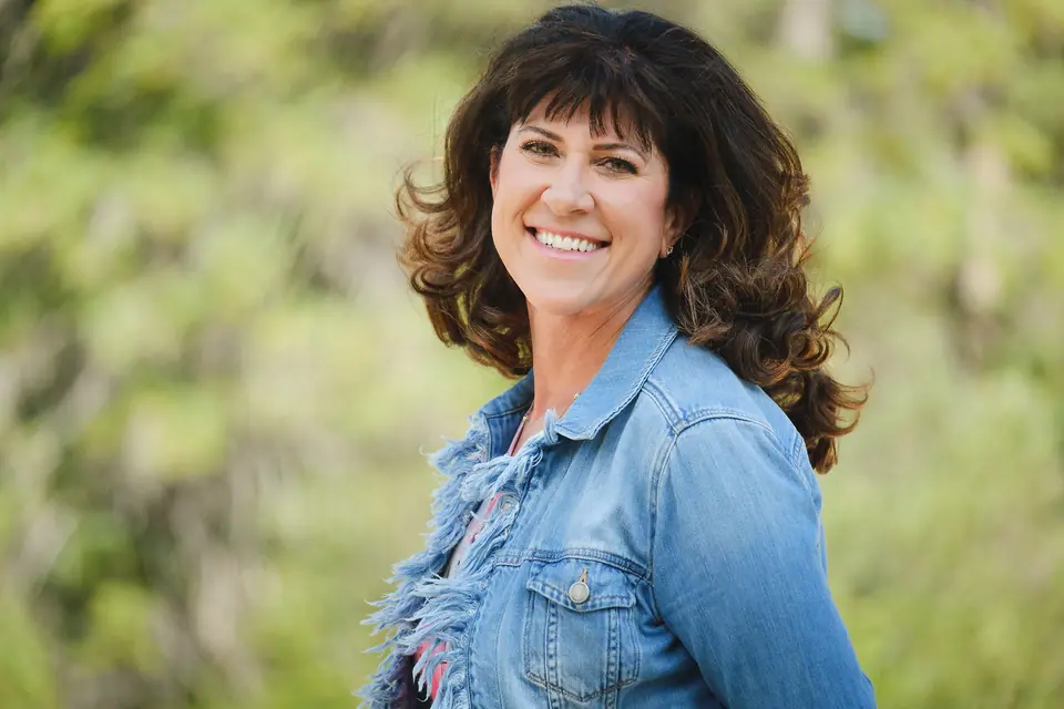 Outdoor portrait of a smiling woman with curly hair in a denim jacket