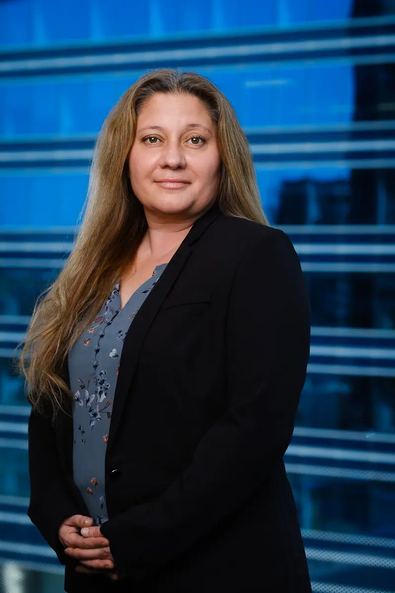 Corporate portrait of a woman in a blazer in front of a glass tower