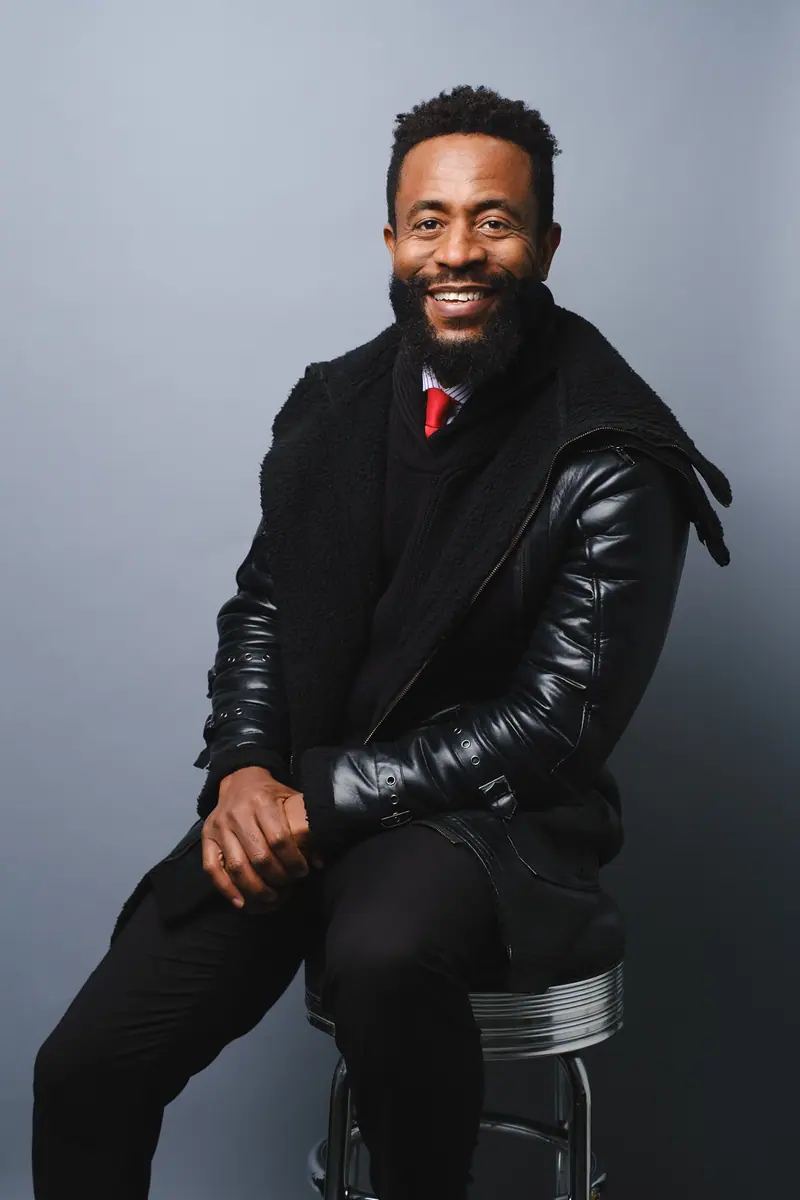 Seated portrait of a smiling man in a black leather jacket