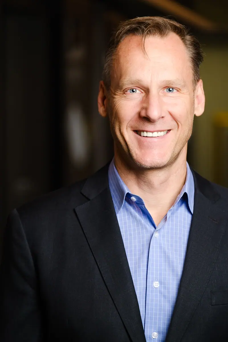 Portrait of a smiling man in a blazer against a dark background