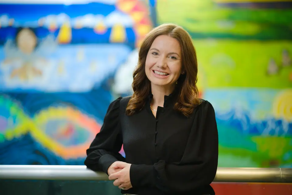 On location portrait of a smiling woman in front of a colourful mural