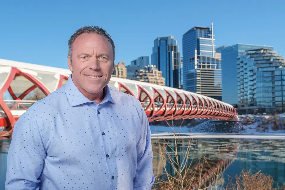 On location portrait of a man by the Peace Bridge with the downtown Calgary skyline