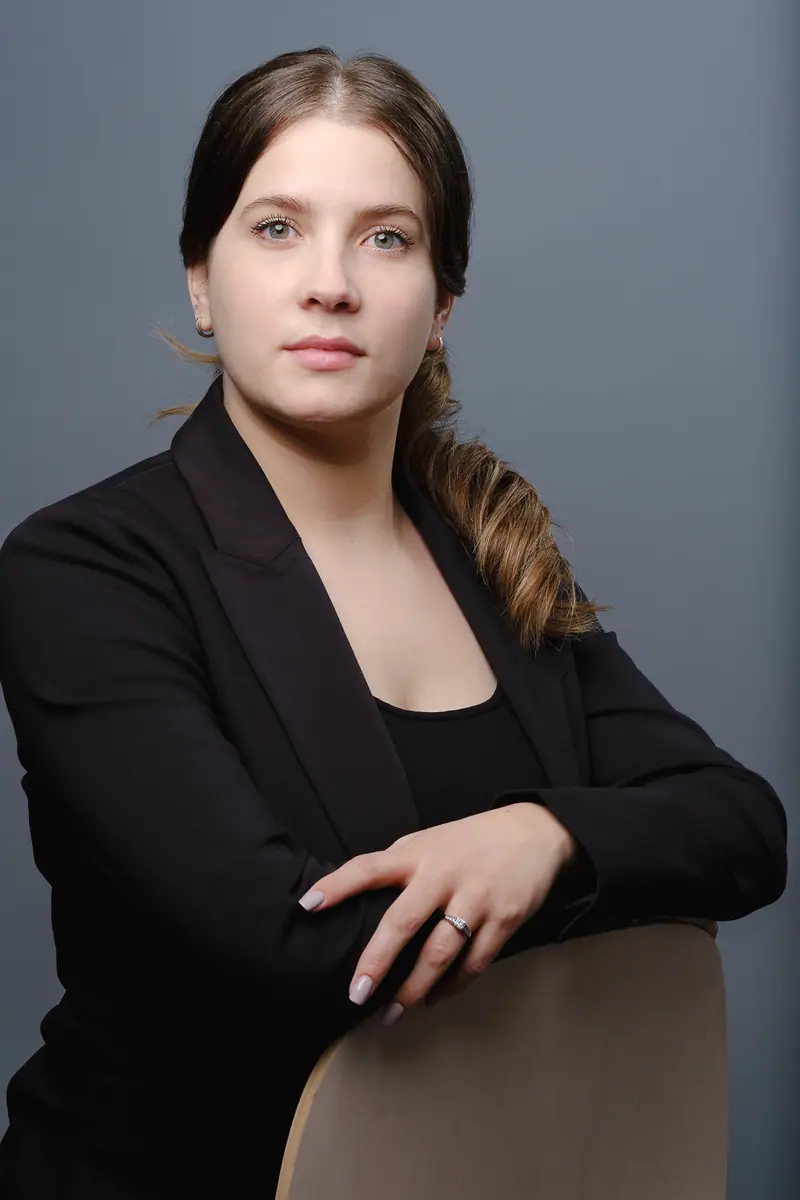 Seated portrait of a woman in a black blazer leaning on a chair